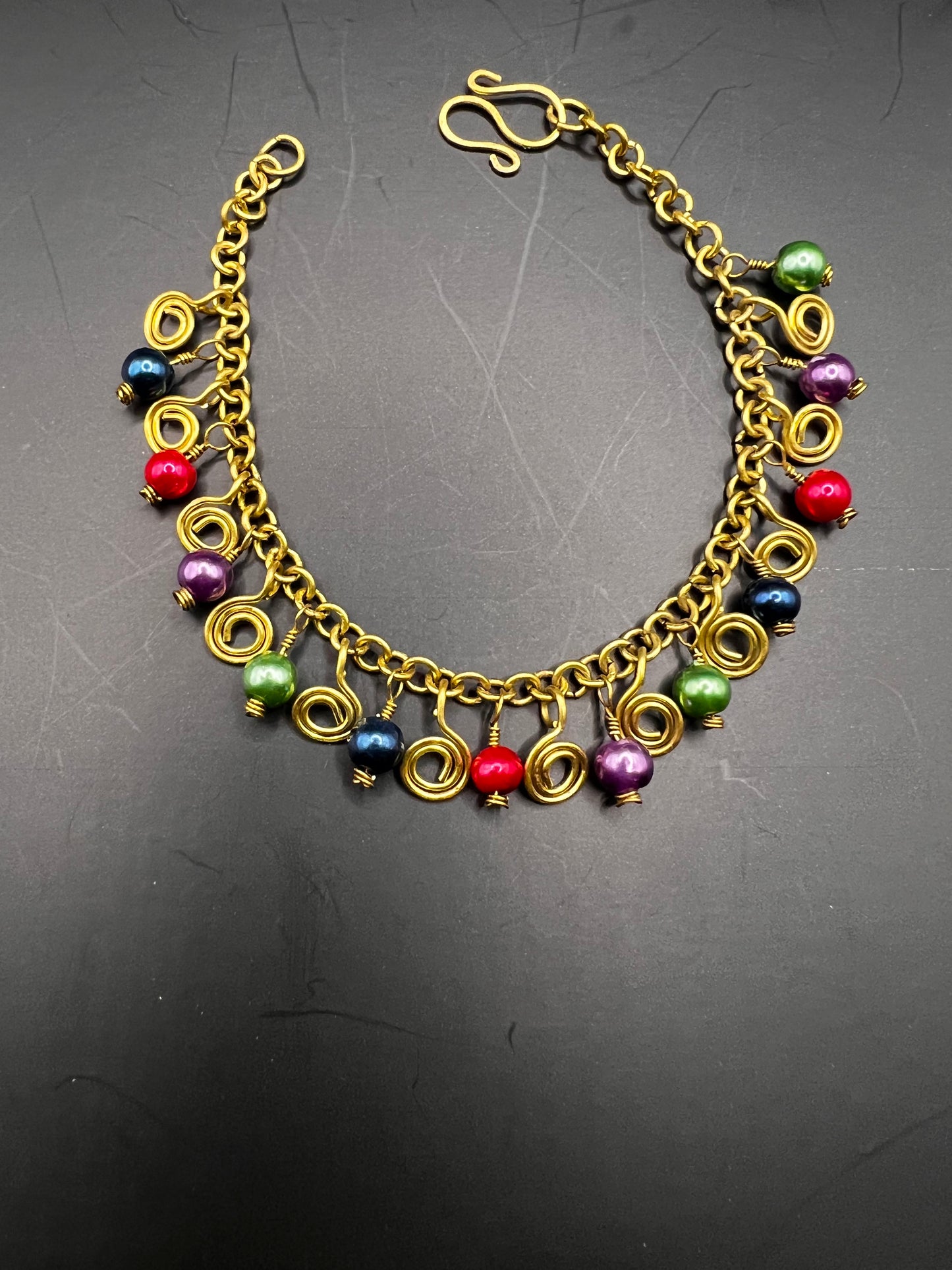Gold charm bracelet with multicolored beads & gold swirls