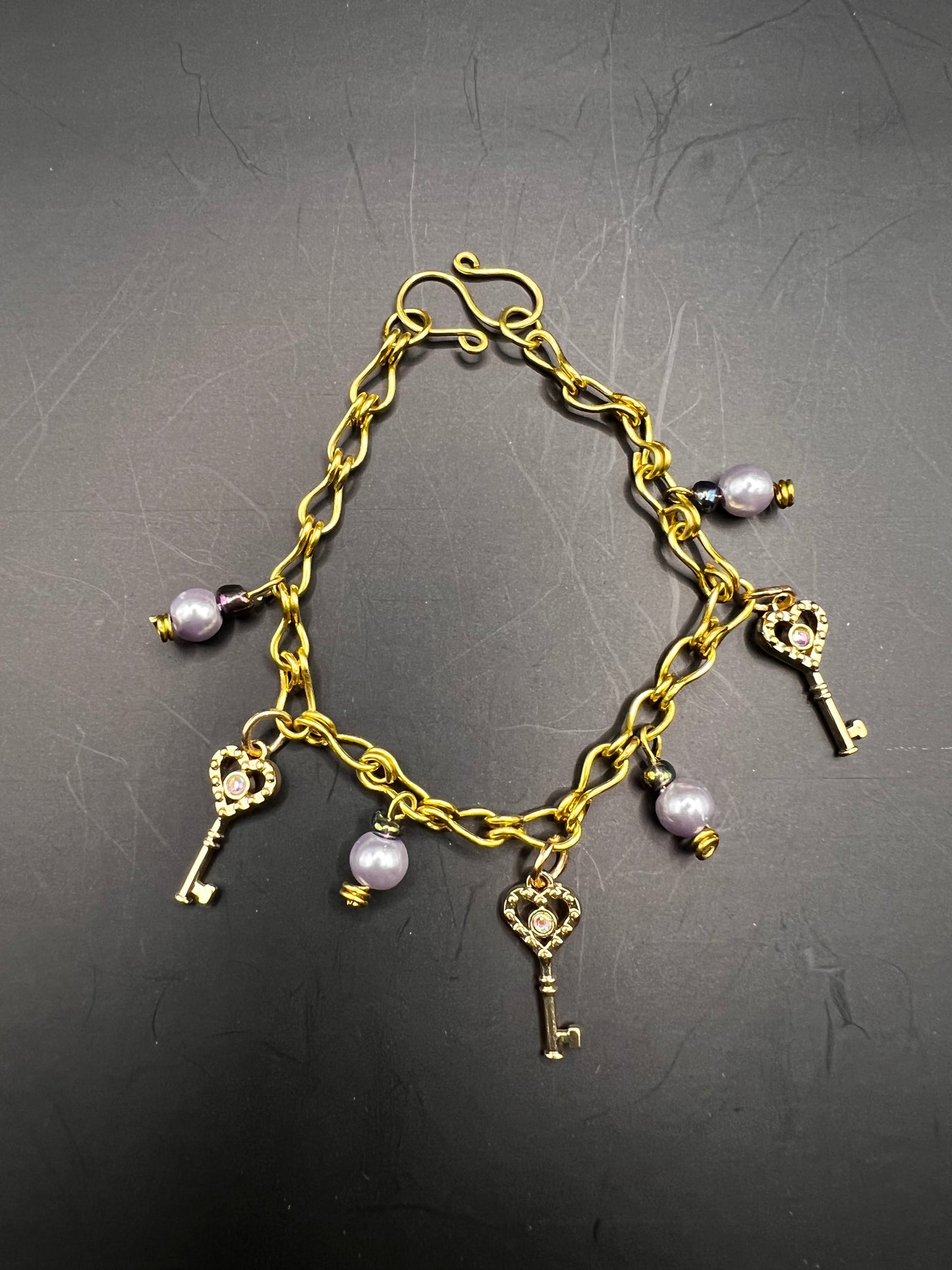 Gold charm bracelet w/ lavender beads, charms & gold keys