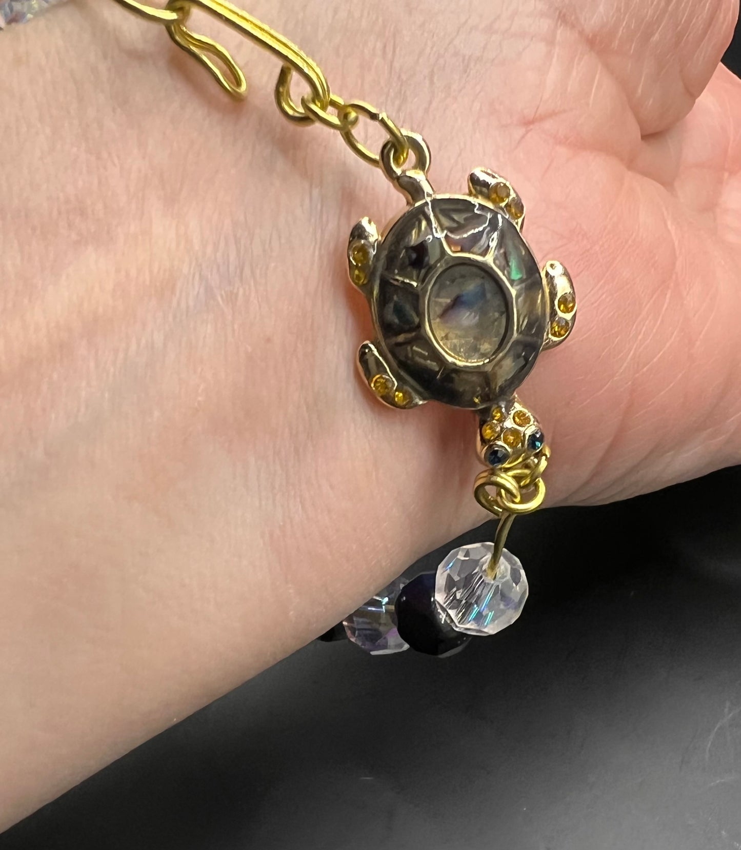 Gold cuff bracelet with multicolored beads which are also iridescent & turtle embellishment.