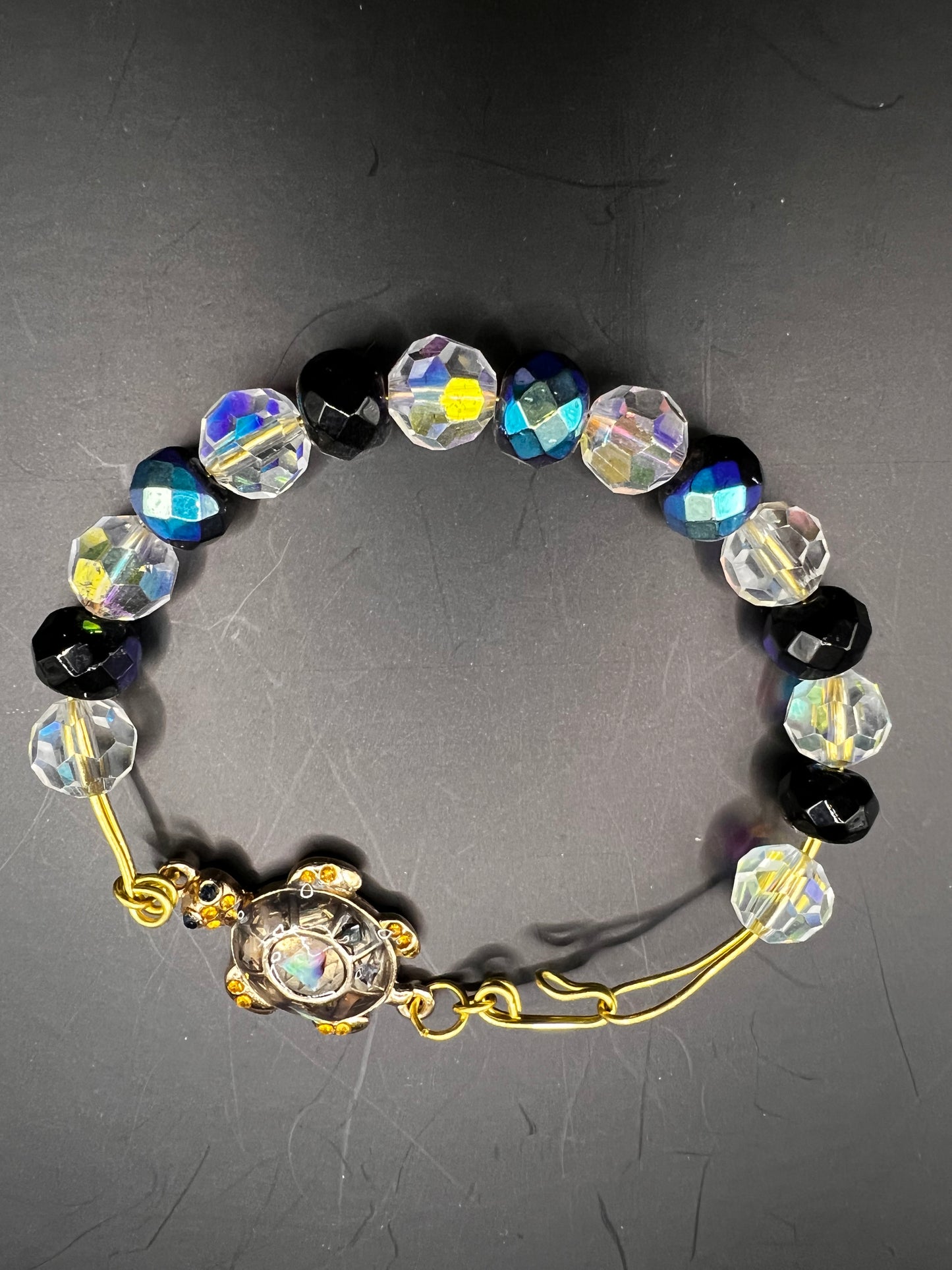 Gold cuff bracelet with multicolored beads which are also iridescent & turtle embellishment.