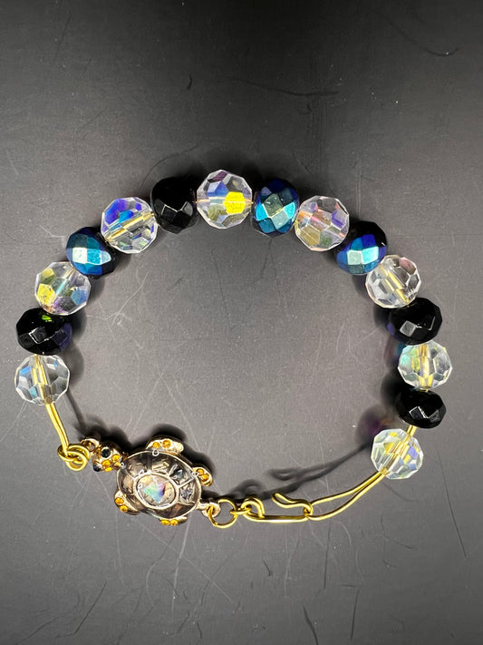 Gold cuff bracelet with multicolored beads which are also iridescent & turtle embellishment.