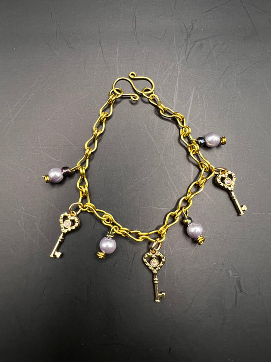 Gold charm bracelet w/ lavender beads, charms & gold keys